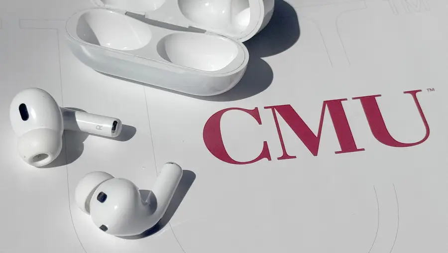 earbuds and case displayed on a table with a CMU logo