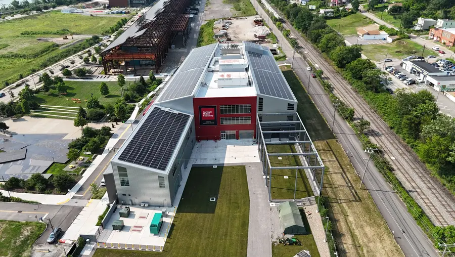 A drone photo from high above the Robotics Innovation Center shows the entire building and the solar array on the roof, as well as the roads and railroad tracks alongside the building and parts of Hazelwood Green and Hazelwood nearby.