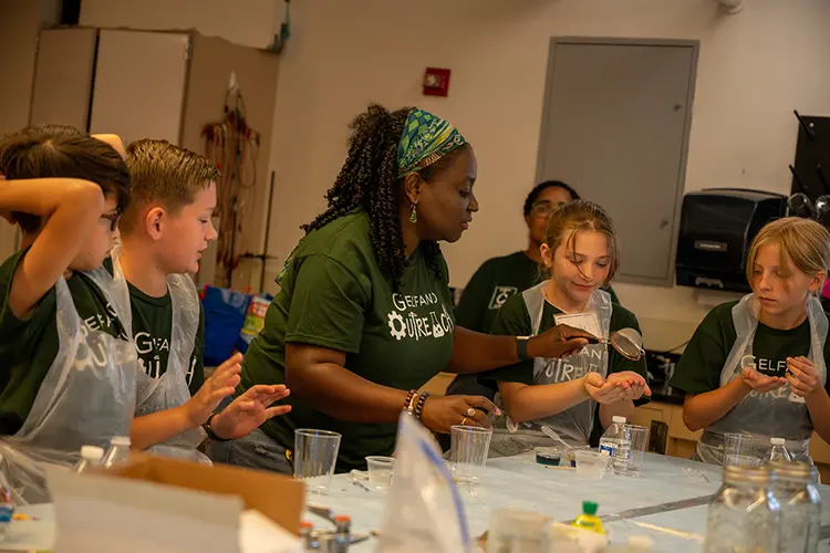 A woman working at a lab table with children on either side