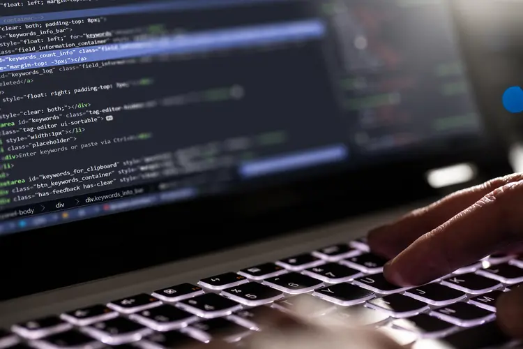 A close up of hands typing computer code on a keyboard.