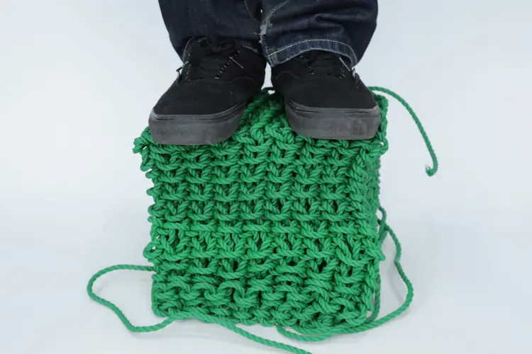 A person stands on a knitted cube made with a new fabrication technique.