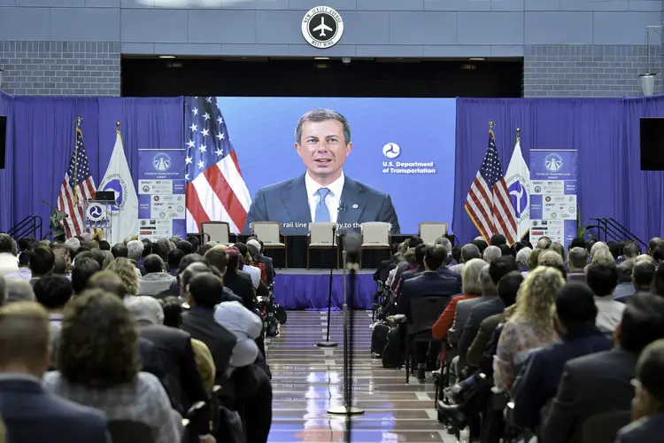 U.S. Secretary of Transportation Pete Buttigieg appears on screen at transportation summit