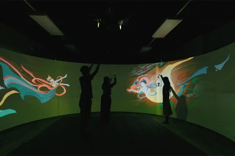 People in front of a large, colorful interactive screen. 