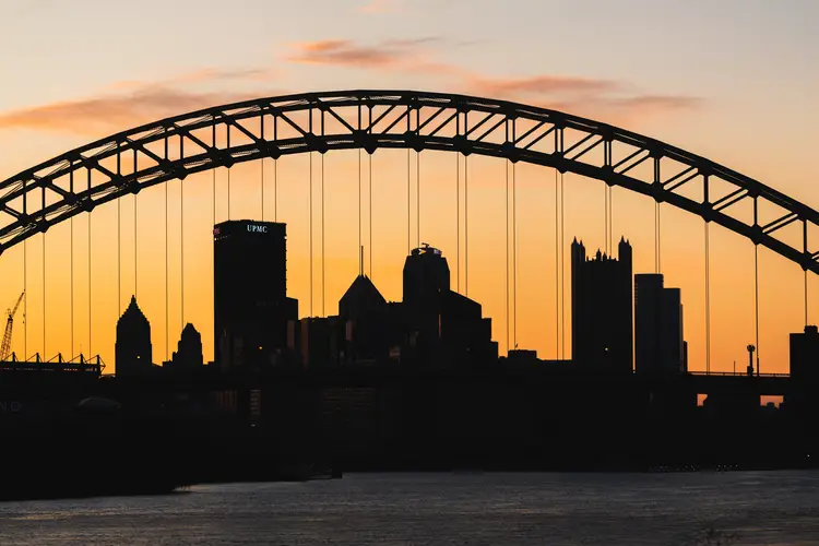 The city of Pittsburgh, seen silhouetted through a bridge. 