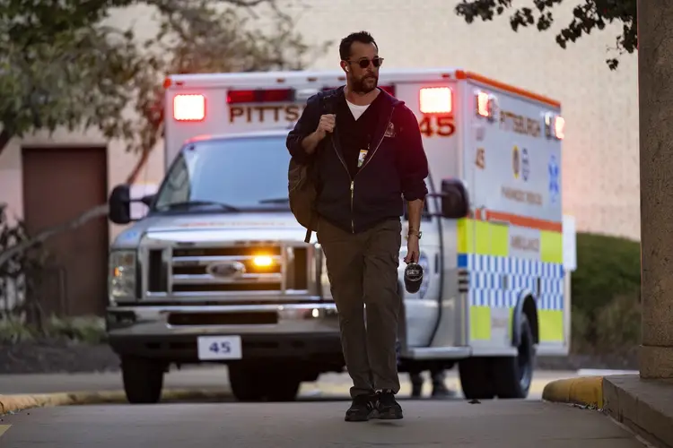 A man walking in front of an ambulance 