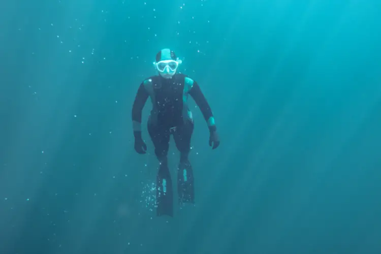 A freediver in a wetsuit swims underwater