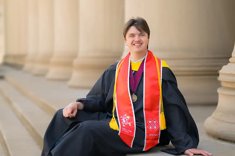 graduate in gown seated on Mellon Institute steps