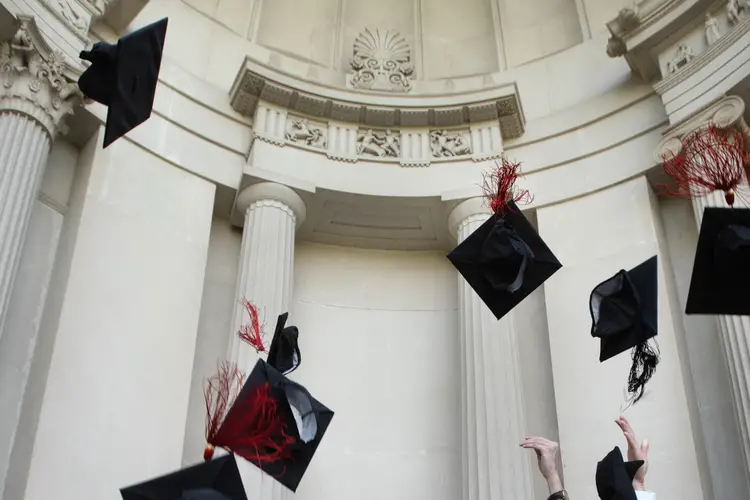 CMU grads throw their caps into the air in front of the College of Fine Arts building. 