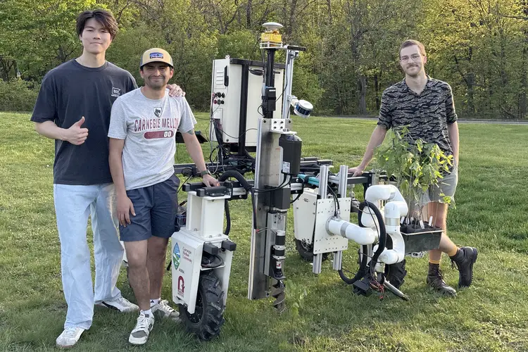 Three students stand next to a robot. 