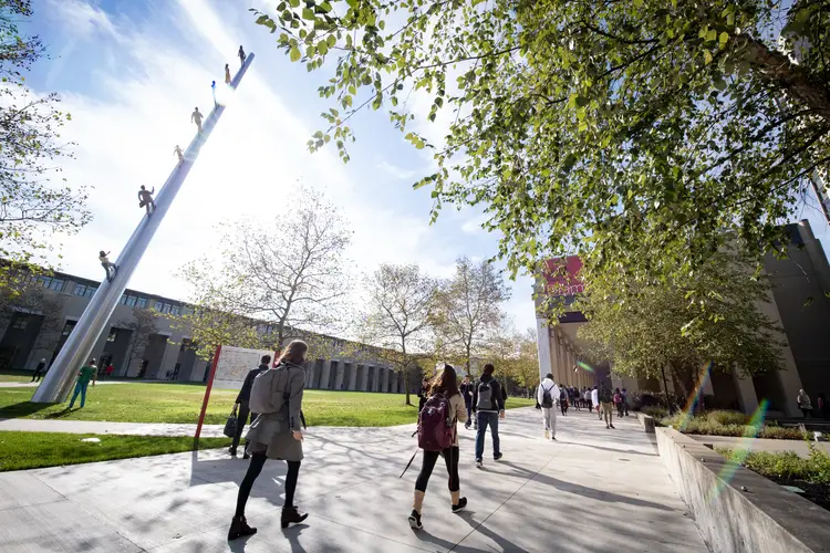 Students walk past "Walking to the Sky" on CMU campus on a fall day. 