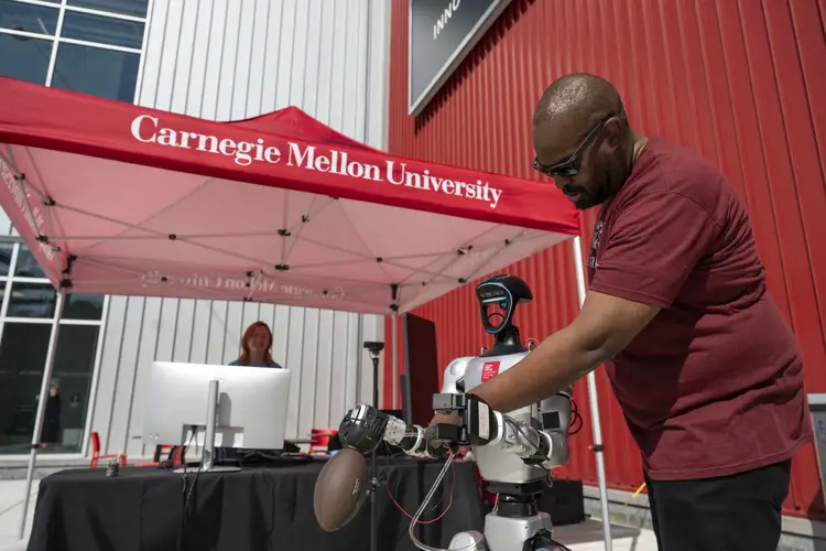 A person looks over a football-throwing robot. 