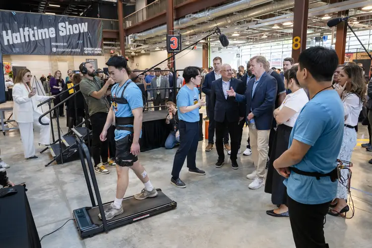 People watch a demonstration involving someone walking on a treadmill. 