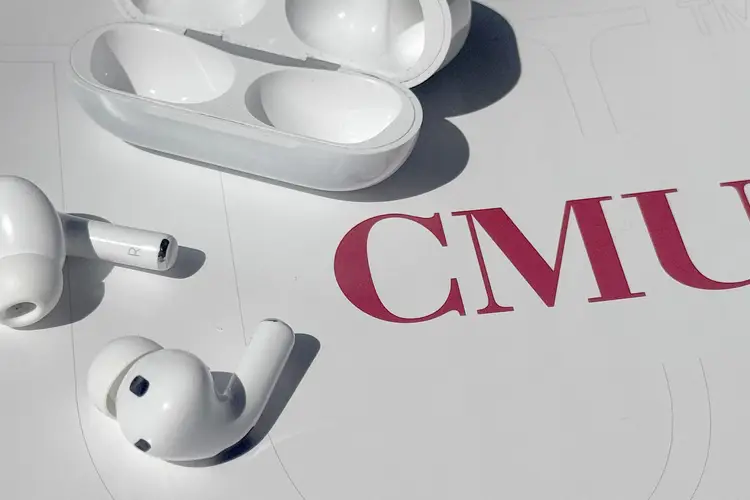 earbuds and case displayed on a table with a CMU logo