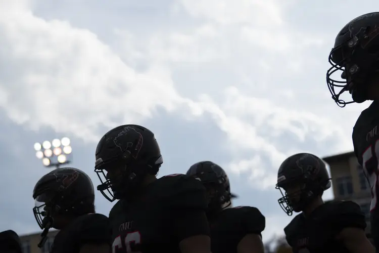 Football player silhouettes against a cloudy sky